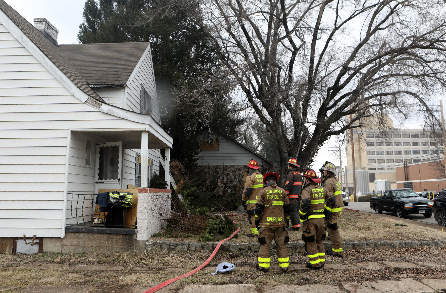 Firefighters stand outside a home on East Third Street